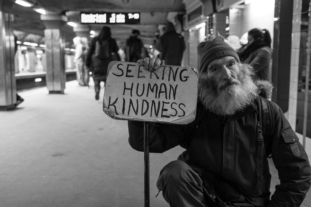 man holding a sign "seeking human kindness"